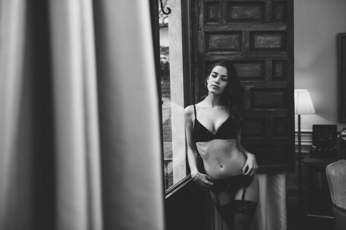 Seksi mlada ženska v perilo poziranja v bližini okna